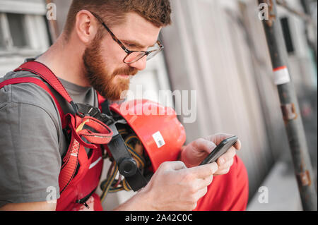 Baustelle Arbeiter sitzen hoch auf dem Gerüst-, Rast- und mit Handy Stockfoto