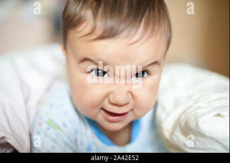 Portrait von baby boy wütend, wütend, runzelte die Stirn und agressive liegen auf Decke. Lustiges Gesicht des neugeborenen Kindes Stockfoto