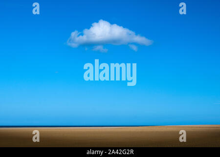 Eine weiße Wolke über einem leeren Strand. Stockfoto