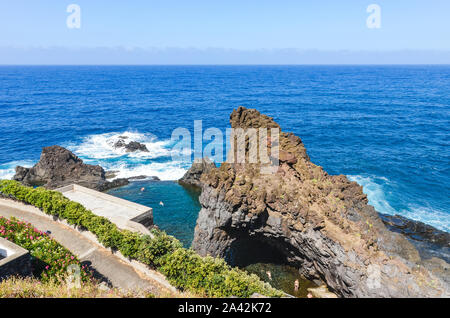 Menschen Schwimmen in natürlichen Pools in den Atlantischen Ozean in Seixal, Madeira, Portugal. Pool von vulkanischen Gesteinen aus dem offenen Meer umgeben ist. Blick von oben. Sommer Urlaub. Stockfoto