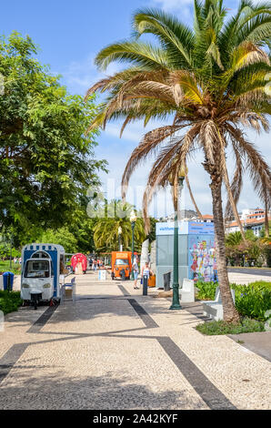 Funchal, Madeira, Portugal - Sep 10, 2019: City Promenade in der Hauptstadt Madeiras, der portugiesischen Stadt. Cobbled Pavement, grüne Vegetation, Palmen und die Menschen auf den Straßen. Sonnigen Tag. Das tägliche Leben. Stockfoto