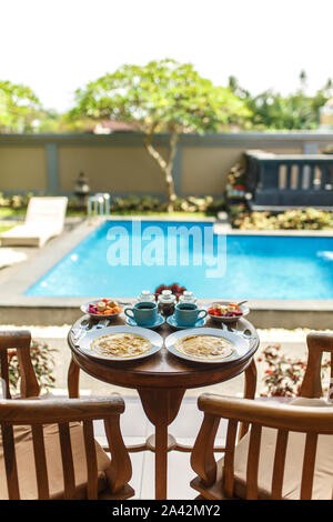 Balinesische tropisches Frühstück mit Obst, Kaffee und Omelett für zwei Personen. Auf der Straße in der Nähe des Pool. Stockfoto