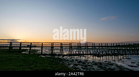 Aberlady Nature Reserve, East Lothian, Schottland, Vereinigtes Königreich, 11. Oktober 2019. Sonnenuntergang am Naturschutzgebiet, mit dem hölzernen Fußgängerbrücke über das Wattenmeer bei Ebbe Stockfoto