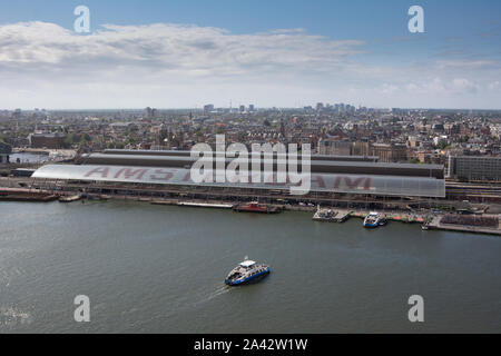 Der Hauptbahnhof von Amsterdam aus der Luft gesehen, mit einer Fähre über den Fluss IJ Stockfoto