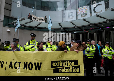 Umweltaktivisten mit einem großen Banner vor dem BBC-Gebäude Haupteingang während der Demonstration. Aussterben Rebellion Umweltaktivisten außerhalb der BBC in London versammelt das Bewusstsein für die Umwelt- und Klimakrise zu heben und die wahre Erfassung der ökologischen Krise zu verlangen. Stockfoto