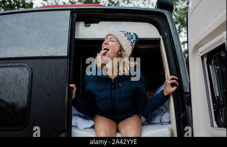 Porträt einer Frau mit ihrer Zunge im Regen beim Camping Stockfoto