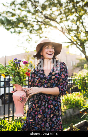 Gerne Frau mit frischen Blumen in städtischen Umgebung Stockfoto