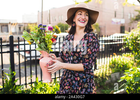 Glückliche Frau in städtischen Garten lächelnd mit frischen Blumen Stockfoto