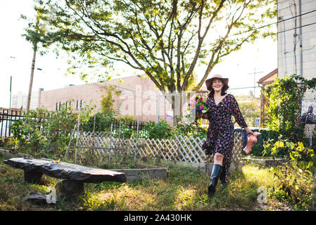 Glückliche Frau wandern in städtischen Garten mit frischen Blumen Stockfoto