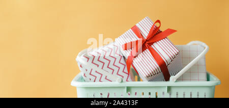 Die Geschenk- oder Geschenkboxen im Korb auf gelbem Hintergrund. Kopierraum des weihnachts- und Neujahrskonzepts. Stockfoto