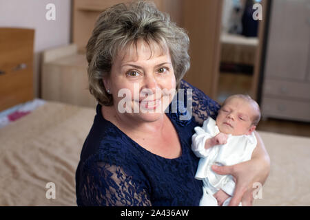 Kleiner Junge in den Armen der Großmutter zu Hause Stockfoto