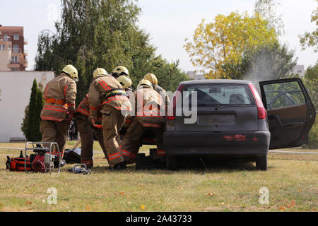 Feuerwehrmänner, die Teilnahme an einer Schulung, wo sie Feuer aus einem Auto Löschen in einem anderen Fahrzeug zusammengestoßen. Rauch aus einem blauen Auto nach einer Explosion. Stockfoto