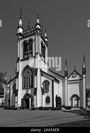 Lunenburg, Nova Scotia, Kanada - St. John's Anglican Church, hoch in einem Tischler gotischen Stil verziert. Eine Person in den klerikalen Gewand verlässt die Kirche. Stockfoto