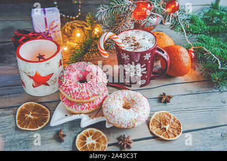 Rosa donuts liegen auf dem Tisch neben Eierlikör und Mandarinen. Das neue Jahr feiern. Stockfoto