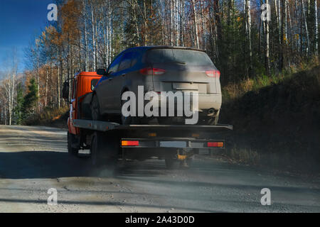 Abschleppwagen Fahrten über einen Waldweg vor dem Hintergrund der Herbst Wald. Hilfe auf der Straße transportiert Wrecker gebrochen. Stockfoto