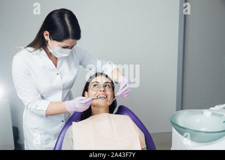 Eine Frau ist die Vorbereitung für eine zahnärztliche Untersuchung. Frau, die Zähne Zahnärzte untersucht. Stockfoto