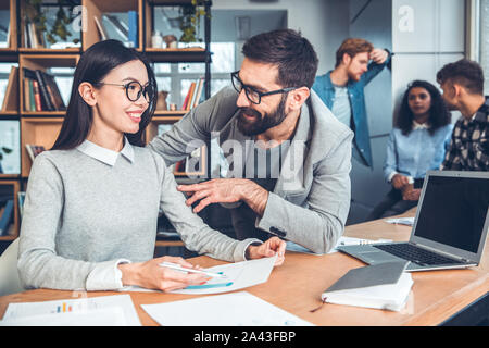 Startupers zusammen arbeiten im Büro Frau in Brillen sitzen im Gespräch mit Kollegen über Dokument zufrieden Stockfoto