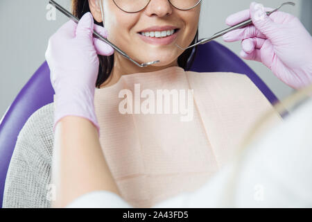 Eine Frau ist die Vorbereitung für eine zahnärztliche Untersuchung. Frau, die Zähne Zahnärzte untersucht. Stockfoto