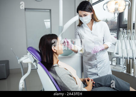 Eine Frau ist die Vorbereitung für eine zahnärztliche Untersuchung. Frau, die Zähne Zahnärzte untersucht. Stockfoto