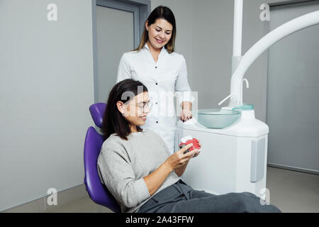 Eine Frau ist die Vorbereitung für eine zahnärztliche Untersuchung. Frau, die Zähne Zahnärzte untersucht. Stockfoto