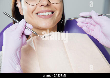 Eine Frau ist die Vorbereitung für eine zahnärztliche Untersuchung. Frau, die Zähne Zahnärzte untersucht. Stockfoto