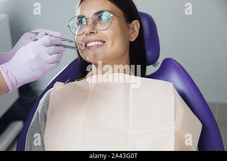 Eine Frau ist die Vorbereitung für eine zahnärztliche Untersuchung. Frau, die Zähne Zahnärzte untersucht. Stockfoto