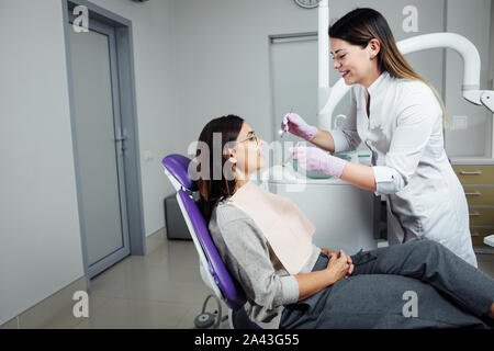 Eine Frau ist die Vorbereitung für eine zahnärztliche Untersuchung. Frau, die Zähne Zahnärzte untersucht. Stockfoto