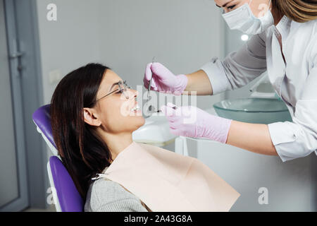 Eine Frau ist die Vorbereitung für eine zahnärztliche Untersuchung. Frau, die Zähne Zahnärzte untersucht. Stockfoto
