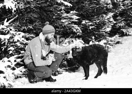 Mann mit Hund Winter mit Schnee im Wald. Freundschaft mit Hunden. Stockfoto