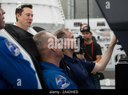 Hawthorne, Vereinigten Staaten von Amerika. 10. Oktober, 2019. NASA-Administrator Jim Bridenstine, rechts, nimmt an einem crew Dragon Flight Simulation mit NASA-Astronauten Doug Hurley, Zentrum, SpaceX Gründer und CEO Elon Musk auf während einer Tour der SpaceX Hauptsitz Oktober 10, 2019 in Hawthorne, Kalifornien aussieht. Credit: Aubrey Gemignani/NASA/Alamy leben Nachrichten Stockfoto