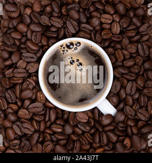 Kaffee Tasse mit schwarzem frisch gebrühten Kaffee unter Kaffeebohnen. Die duftenden Kaffeebohnen. Stockfoto