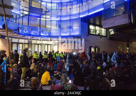 London, Großbritannien. 11. Oktober, 2019. Klima Aktivisten vor dem Aussterben Rebellion, von denen zwei auf ein Glas Brüstung, Block der Haupteingang des neuen BBC Broadcasting House am Abend des fünften Tages der Internationalen Rebellion Proteste. Sie forderten, dass der Fernsehveranstalter "Sag die Wahrheit" in Bezug auf die Klima Notfall. Credit: Mark Kerrison/Alamy leben Nachrichten Stockfoto