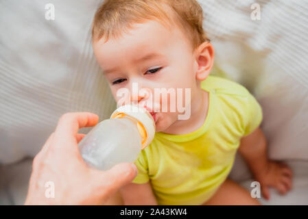 Adorable 1 Jahr altes Baby getränke Flasche Formel Getränk für Kleinkinder, durch ihre einzelnen Vater geholfen. Stockfoto