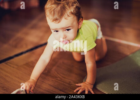 Baby Mädchen mit einem hübschen Gesicht krabbeln auf dem Holzboden ihres Hauses, retro Tönen und blasse Farben. Stockfoto