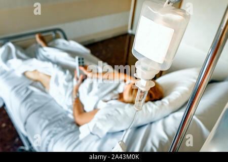 Kochsalzlösung Infusionsbeutels hängend an das Bett eines kranken Frau. Stockfoto