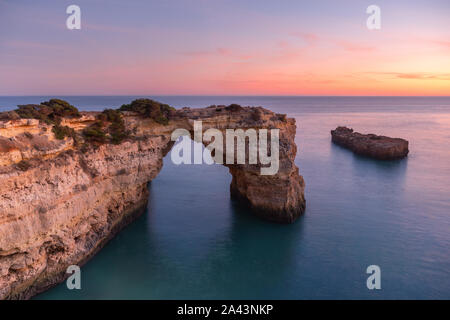 Algarve Strand bei Sonnenuntergang. Liebevolle Moment unter Natural Arch in Stein gemeißelt ist eine touristische Attraktion an der Südküste von Portugal. Panoramablick vom Stockfoto