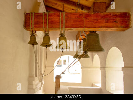 Glocken in verschiedenen Größen hängen von einer dicken Holzbalken. Stockfoto