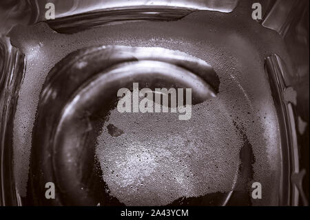 Top-down-Sicht auf Platz unten Leer Bier Glas auf dunklen Tischfläche. Blasen Links aus dem Bier Kopf oder Kragen, cremiger Schaum auf dem Glas. Stockfoto