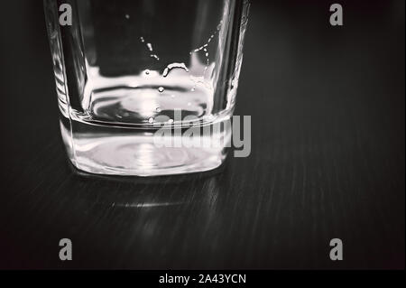 Platz unten Leer Bier Glas auf dunklen Tischfläche. Blasen Links aus dem Bier Kopf oder Kragen, cremiger Schaum auf dem Glas. Stockfoto