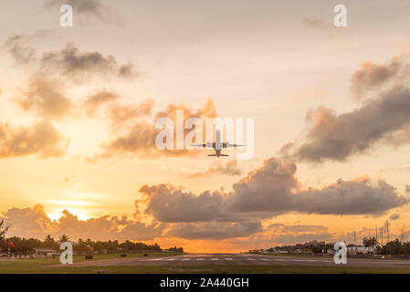 Ebene, die bei Sonnenuntergang auf St. Maarten Stockfoto