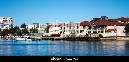 Großes Apartment am Wasser Häuser, Eigentumswohnungen in suburban Gemeinschaft am Flussufer mit Booten an der Wharf, blauen Himmel im Hintergrund günstig Stockfoto