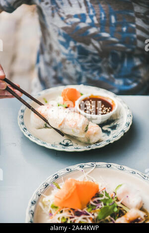 Mann, Abendessen im vietnamesischen Restaurant. Mann essen vietnamesischen vegan Reis Papierrollen mit Stäbchen aus schöne asiatische Porzellan Teller. Asiatische, Stockfoto