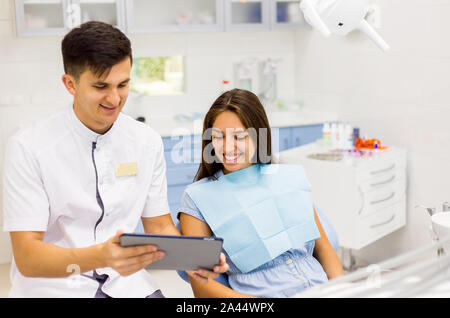 Junge Zahnarzt in der Zahnarztpraxis im Gespräch mit weiblichen Patienten und Vorbereitung der Behandlung. Stockfoto