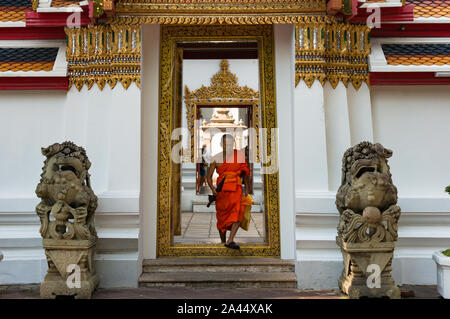 Bangkok, Thailand - Dec 24, 2015: buddhistischer Mönch im orangen Gewand durch die Tür gehen in Wat Pho Tempel Innenhof Stockfoto