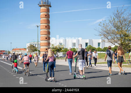 Oktober 6th, 2019, Lissabon, Portugal - Menschen in sonniger Tag neben den Fluss Tejo, Wandern, ausgeführt wird und über Elektroroller. Stockfoto