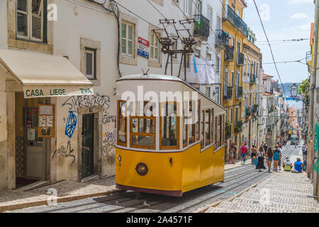 Lissabon, Portugal - 10. AUGUST 2019: Der Elevador da Bica im Zentrum von Lissabon, in dem die legendären gelben Straßenbahn und die umliegenden Gebäude. Menschen können auch Stockfoto