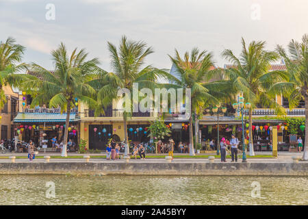 HOI AN, VIETNAM - AM 24. MÄRZ 2017: die Menschen in den Booten auf dem Thu Bon Fluss in Hoi An bei Sonnenuntergang. Gebäude können entlang der Ufer gesehen werden. Stockfoto