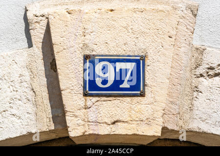 Emaillierte Hausnummer 90 Sieben (97) auf einem Fundament. Stockfoto