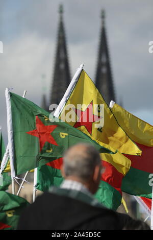 Köln, Deutschland. 12 Okt, 2019. Die Teilnehmer halten Fahnen während der Demonstration top Die Invasion der kurdischen Gebiete" an der Deutzer Werft mit dem Kölner Dom im Hintergrund. 5000 Teilnehmer sind für die Rallye angemeldet. Quelle: David Young/dpa/Alamy leben Nachrichten Stockfoto