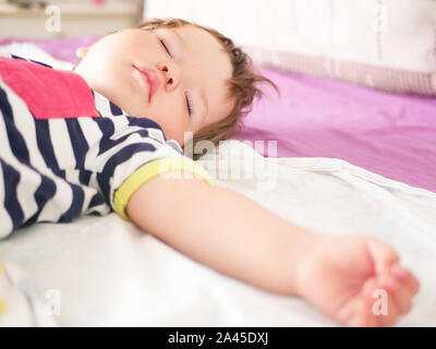 Baby schläft im Bett der Eltern. ausgestreckten Armen erholsamen Schlaf des Babys. close-up. Kind 0-1 Jahre alt. bezaubernd schönen Baby schläft ruhig im Bett, hat eine Stockfoto